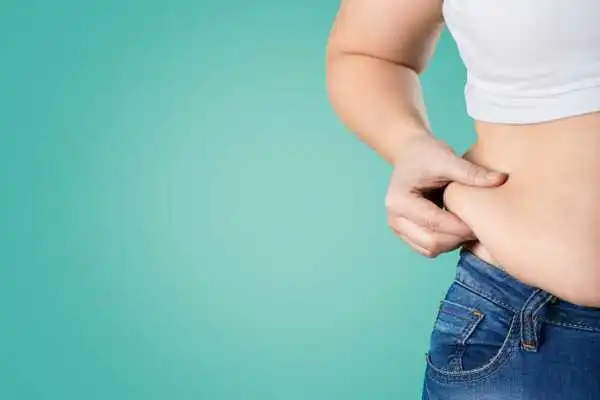 Image of woman pinching her love handles to show weight gain Abbotsbury
